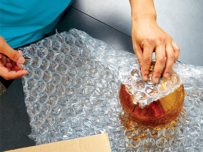 Associate wrapping fragile item in cushion wrap